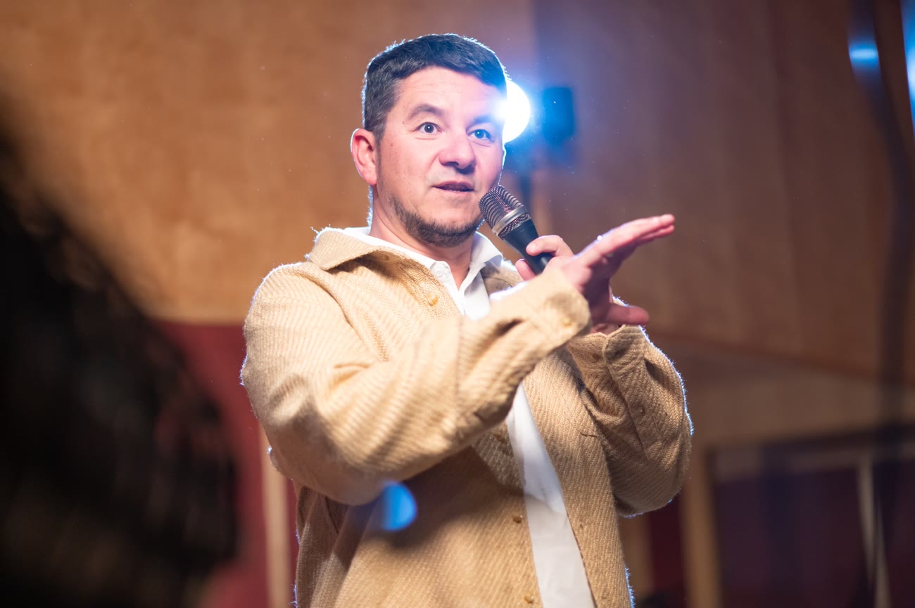 Markus Warscher auf der Bühne mit Mikrofon, Blick ins Publikum.